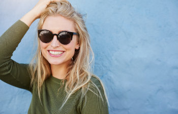 cheerful blonde in sunglasses smiling on blue background, Lawrenceville, GA