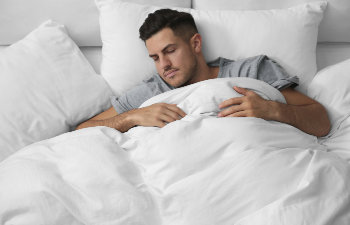 man in gray pajamas sleeps in white sheets, Lawrenceville, GA