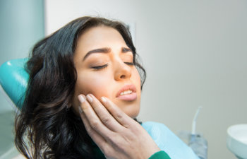 woman with toothache holds by cheek, Lawrenceville, GA